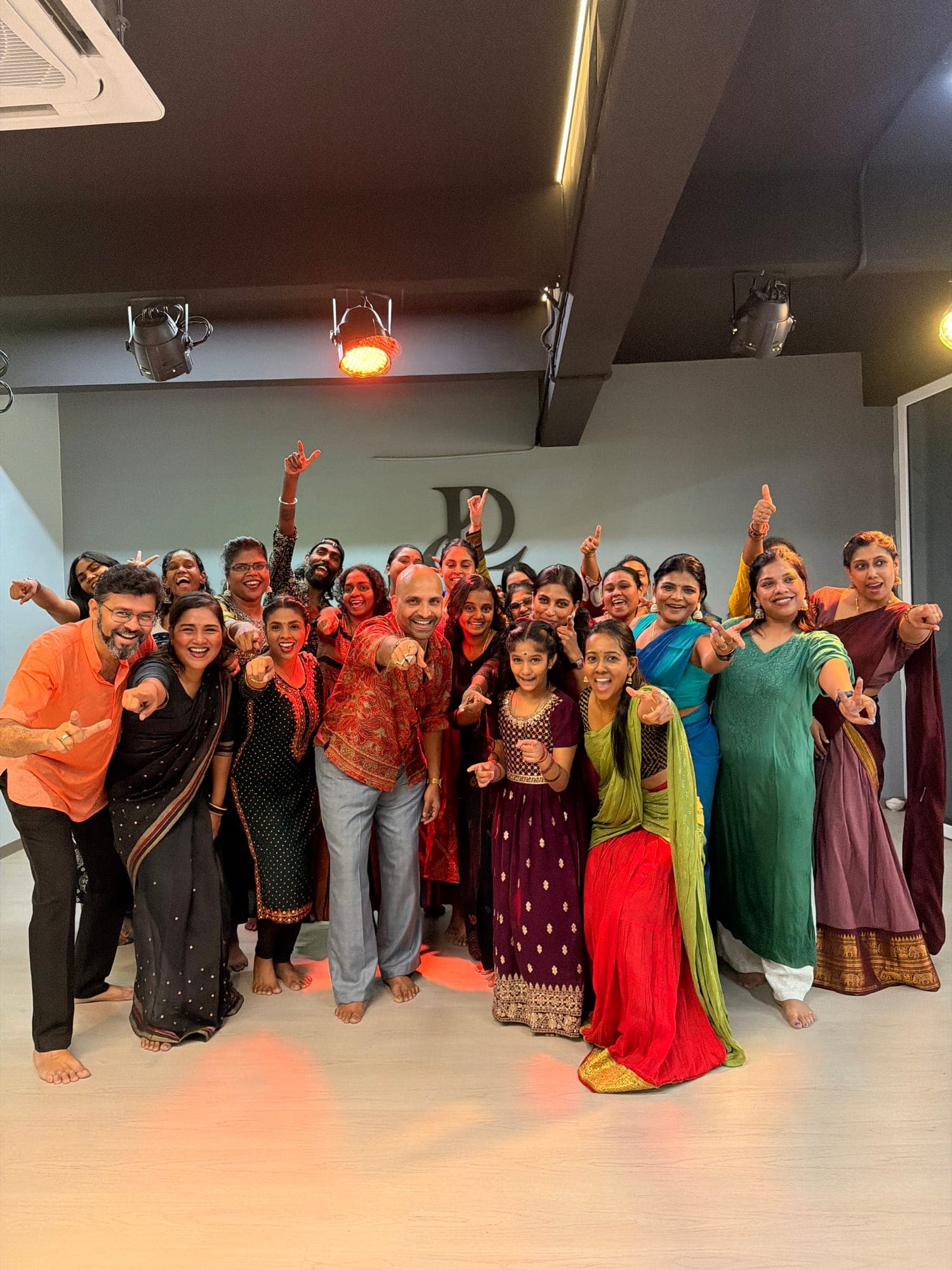 A large group of dancers, many in traditional outfits, posing in the studio at the Salsaamani workshop